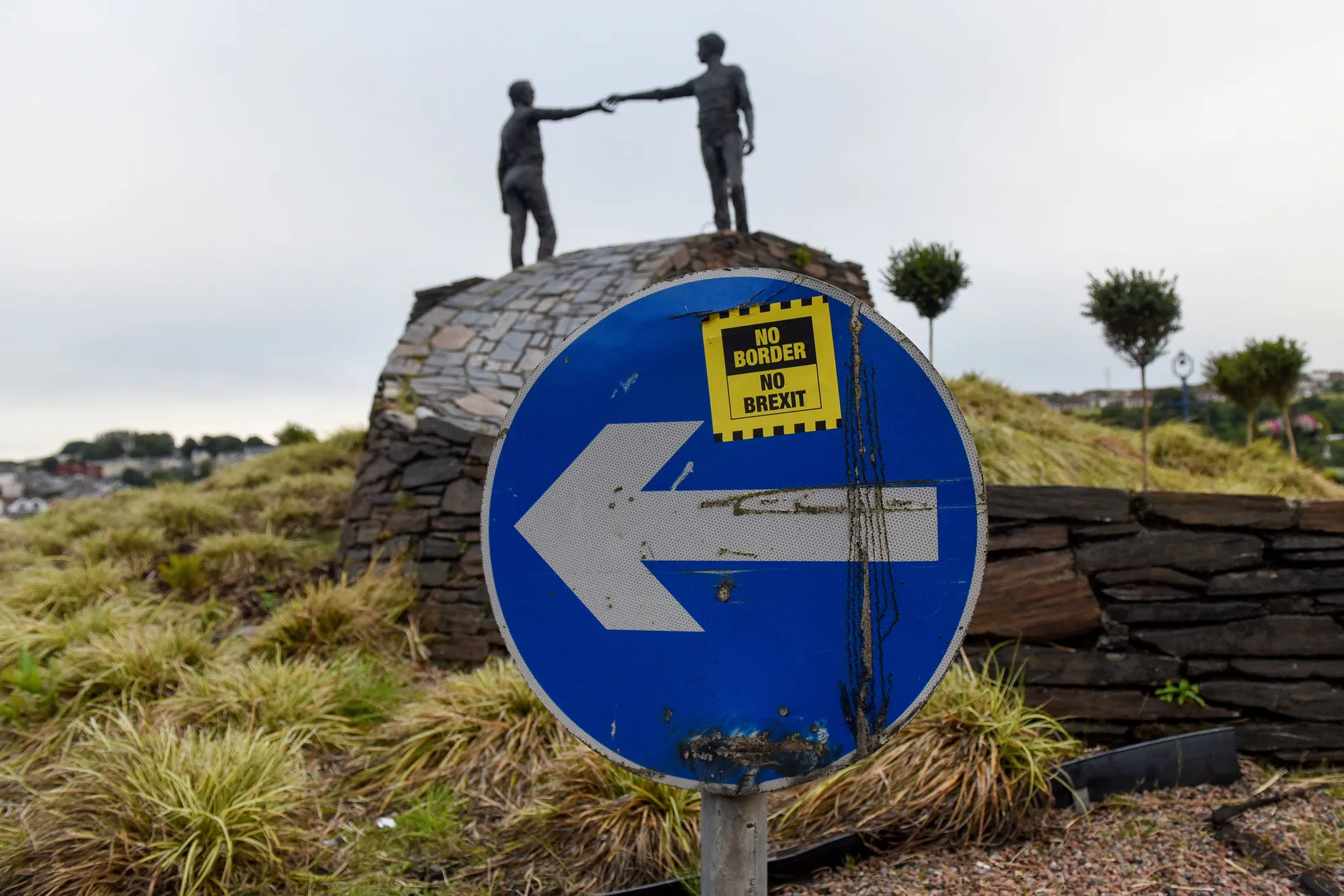 A road sign stands near the 'Hands Across The Divide' sculpture in Derry, Northern Ireland.