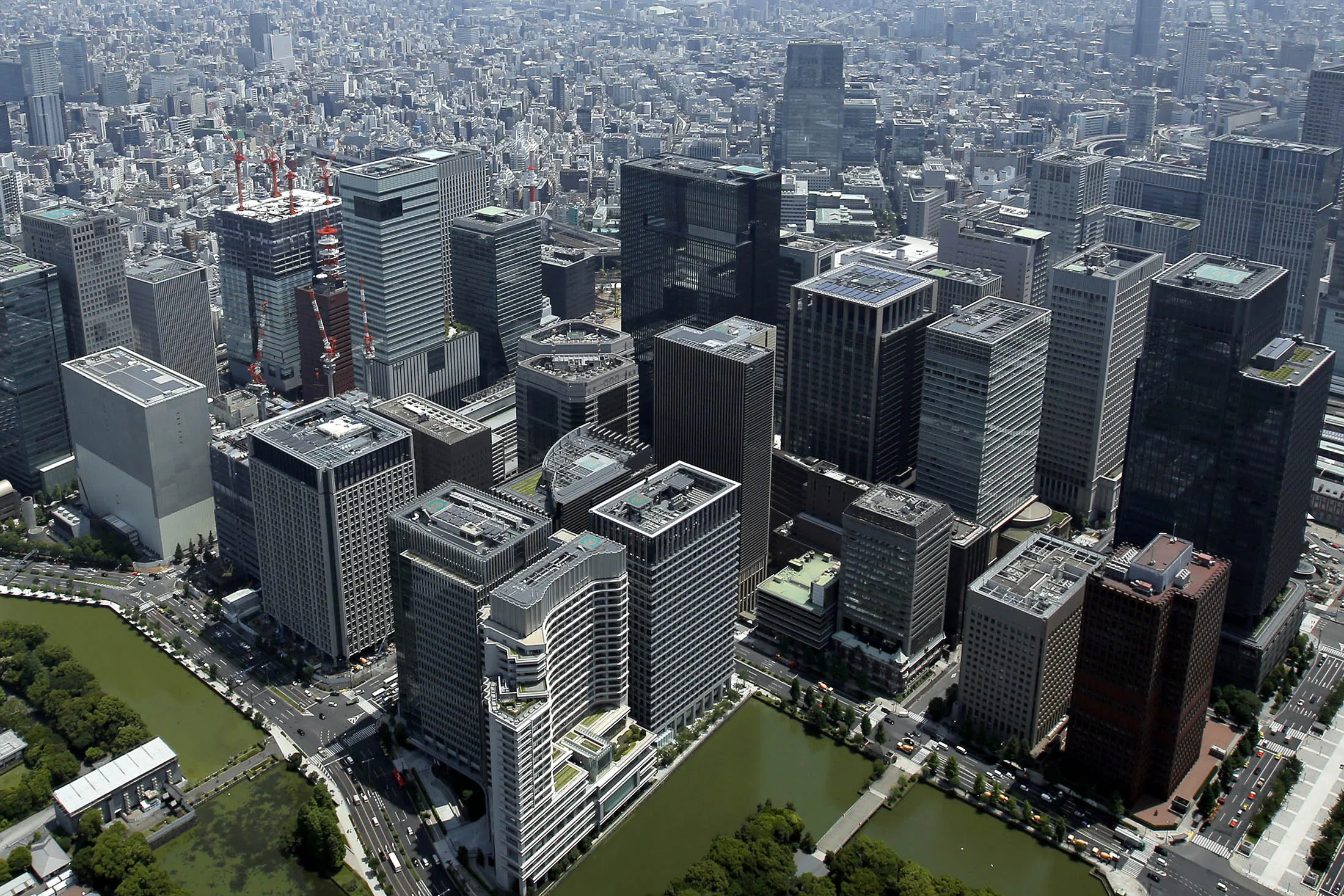 Commercial buildings stand in the Marunouchi and Otemachi districts in this aerial photograph taken in Tokyo, Japan, on Wednesday, June 24, 2015. The Abe administration aims to cap increases in spending as it tries to rein in the world's heaviest debt load while sustaining a recovery from two decades of stagnation.
