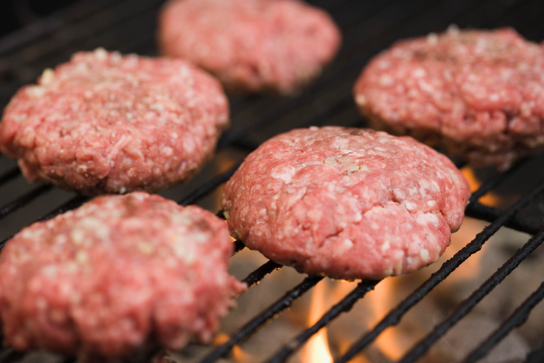 Chef cooking a hamburger patty on an electric grill or griddle