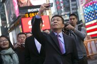 Charles Chao, chief executive officer of Sina Corp., take a photo with his mobile phone during an IPO ceremony for Weibo Corp. at the Nasdaq MarketSite in New York, U.S., on Thursday, April 17, 2014. Weibo Corp., the Chinese microblogging service owned by Sina Corp. and Alibaba Group Holdings Ltd., raised $285.6 million in its U.S. initial public offering after pricing the shares at the low end of a marketed range. Photographer: Scott Eells/Bloomberg *** Local Caption *** Charles Chao