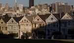 The downtown skyline stands past Victorian homes in San Francisco.
