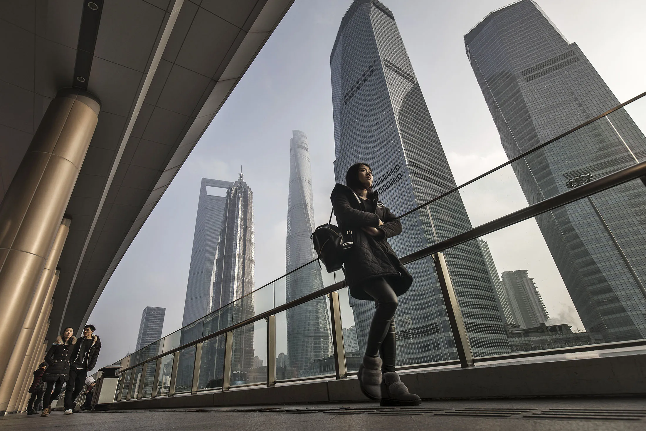 A woman walks down a corridor as skyscrapers of the Pudong area stand in Shanghai.

