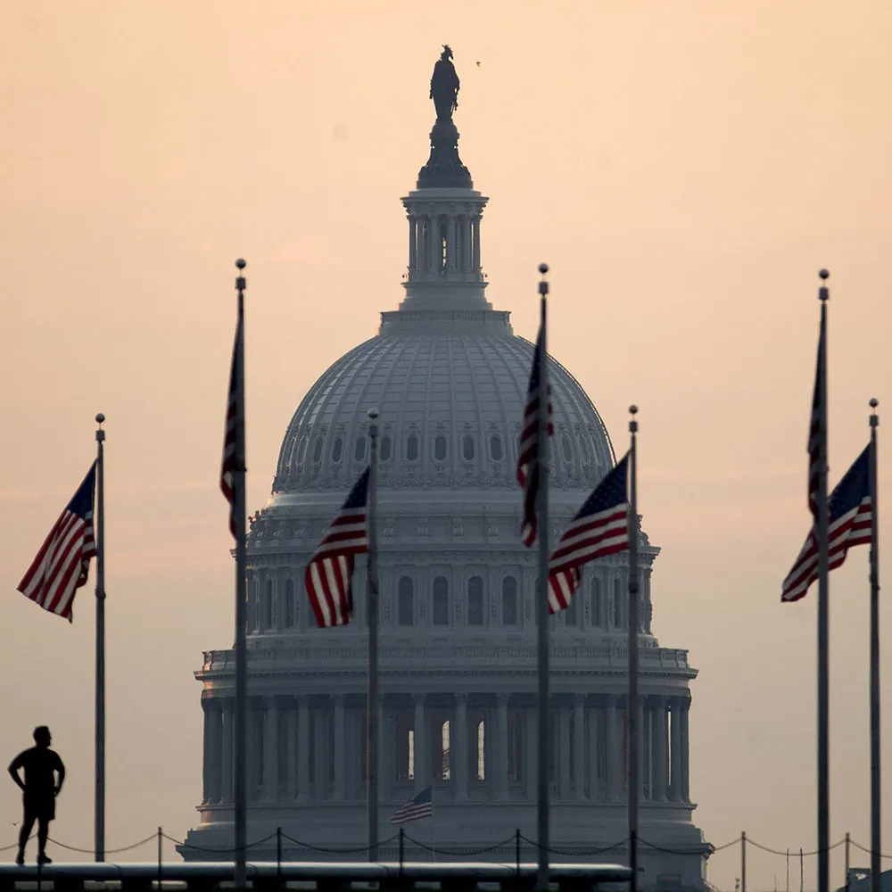 The U.S. Capitol building stands past a runner pausing at the Washington Monument in Washington, D.C., U.S., on Tuesday, July 11, 2017. As Congress returned from its mid-summer break yesterday for a crucial three-week stretch, several obstacles await lawmakers, including an ongoing health-care fight, divisions among Republicans on the basic parameters of a tax bill, and a maelstrom of upcoming deadlines to keep the government running and avert a catastrophic default on U.S. debt.
