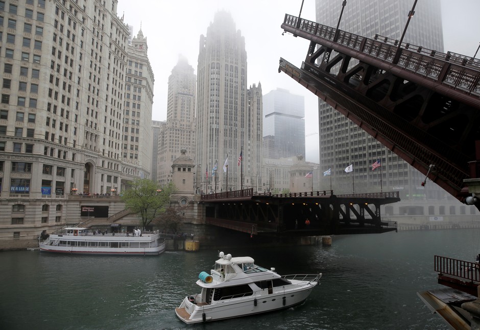 A boat passes under a raised bridge across from the Chicago Tribune building in Chicago, Illinois. 