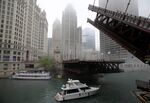 A boat passes under a raised bridge across from the Chicago Tribune building in Chicago, Illinois. 