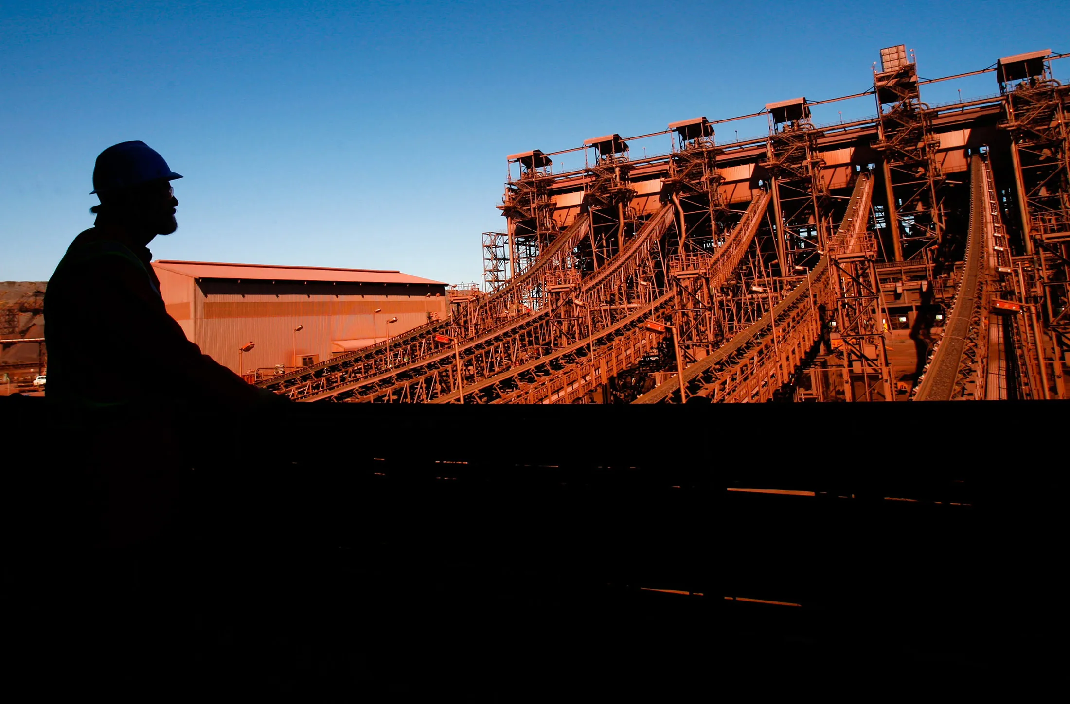 An employee monitors the processing of iron ore along conveyor belts in Shishen, South Africa.
