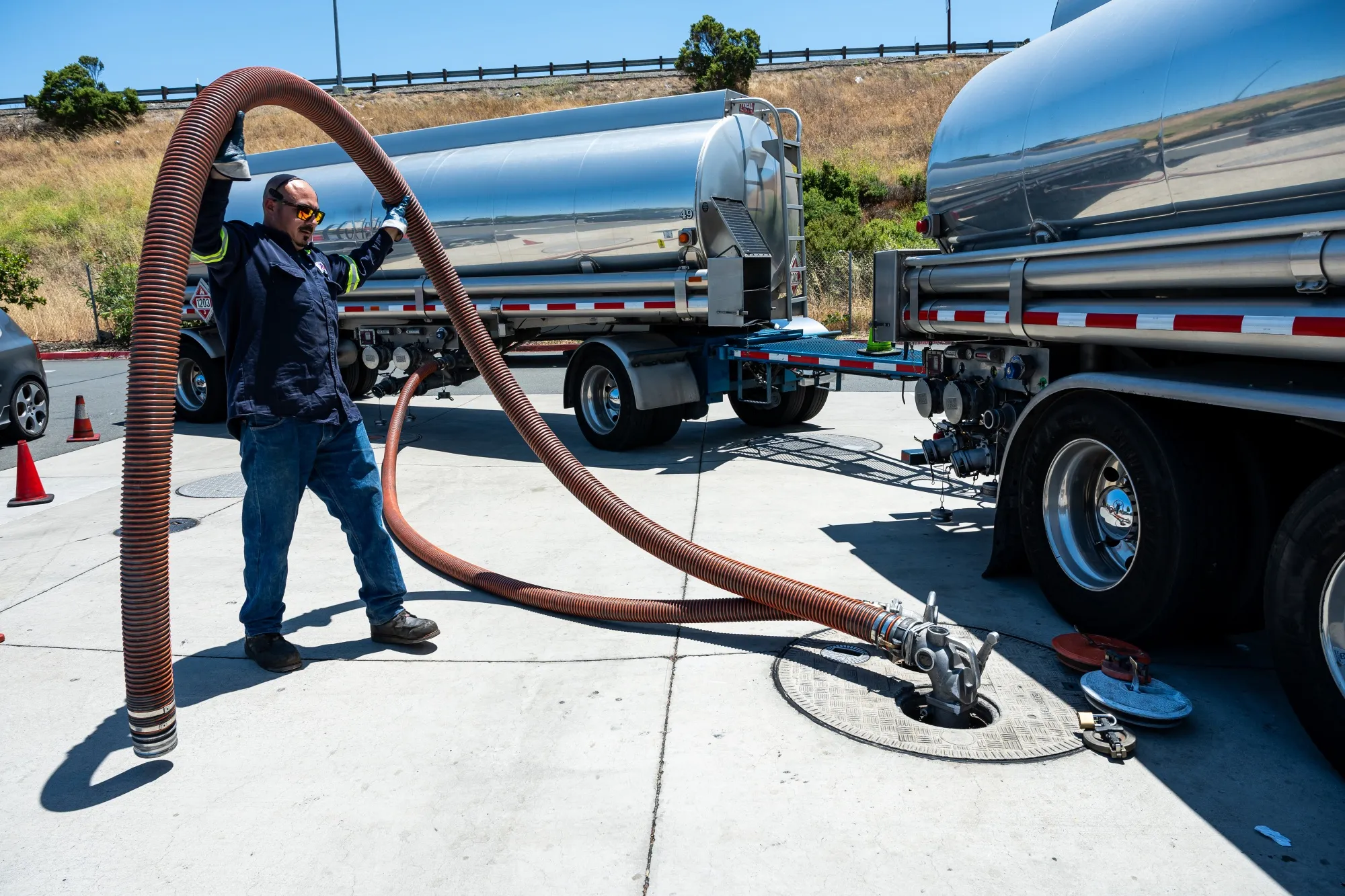 A worker prepares a fuel refill hose at a gas station in Hercules, California.
