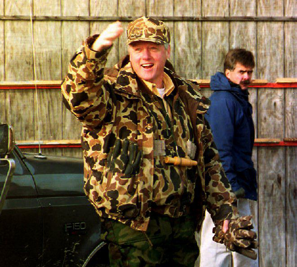 U.S. President Bill Clinton, wearing camouflage clothing and waders, waves to photographers on December 27, 1993, before going duck hunting on Maryland’s Eastern Shore. Photographer: Jennifer Young
