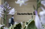 A pedestrian passes a sign at the offices of Deutsche Bank AG in London.