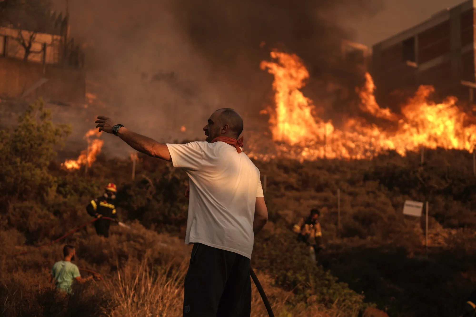 Firefighters and volunteers work to extinguish a burning field during a wildfire in Saronida, south of Athens, Greece, on&nbsp;July 17.