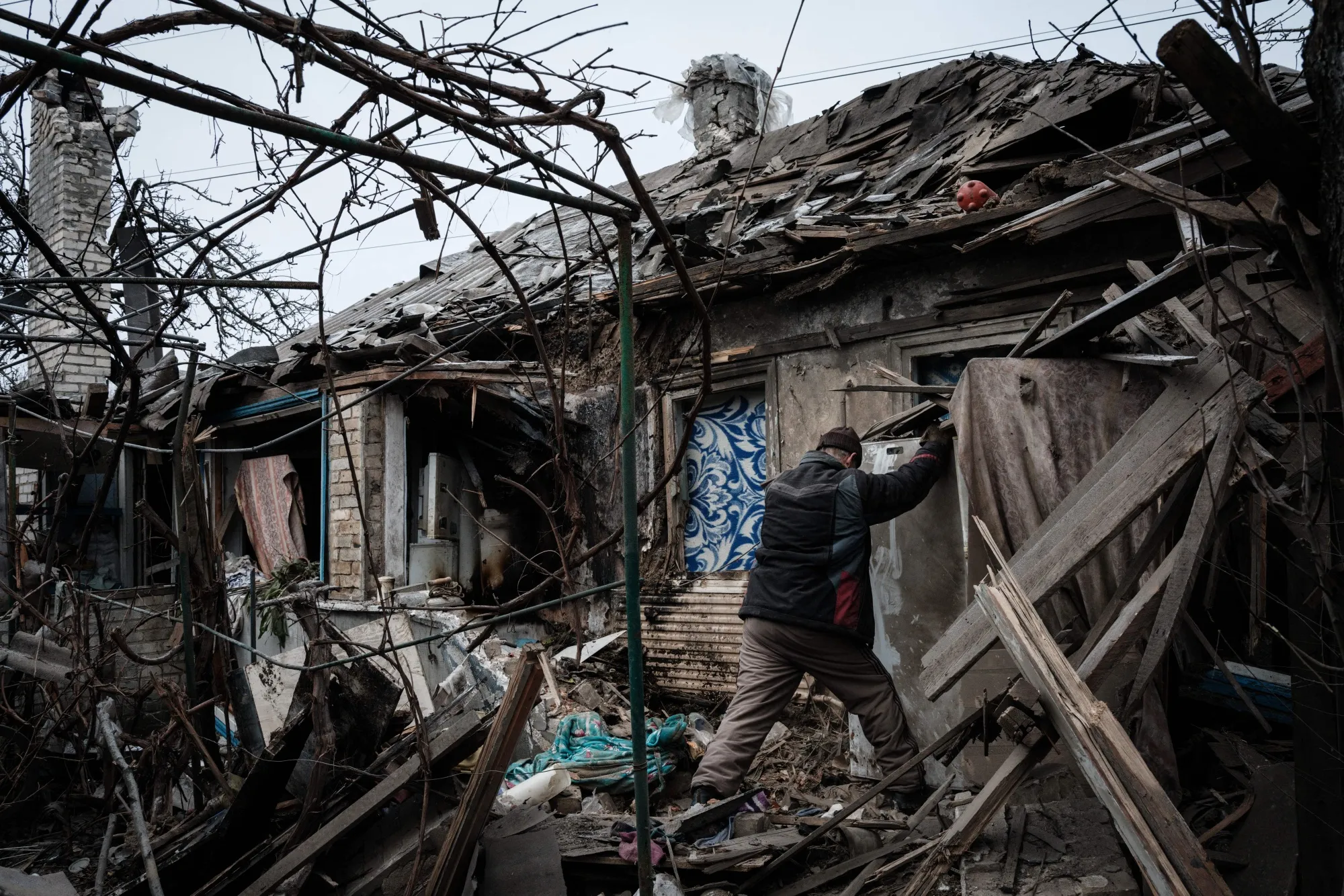 TOPSHOT - Oleksandr Pykhtin (L), 73, tries to open a refrigerator at his house destroyed by a rocket last night as the sounds of gunshots and artillery continue in the distance in Chasiv Yar on January 28, 2023. (Photo by YASUYOSHI CHIBA / AFP) (Photo by YASUYOSHI CHIBA/AFP via Getty Images)