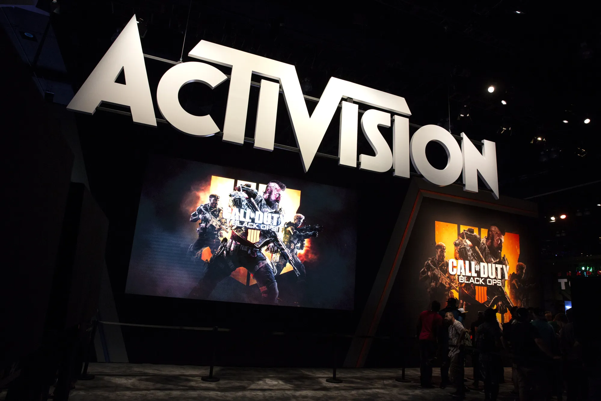 Attendees stand next to signage for Activision Blizzard Call Of Duty: Black Ops 4 video game during the E3 Electronic Entertainment Expo in Los Angeles.
