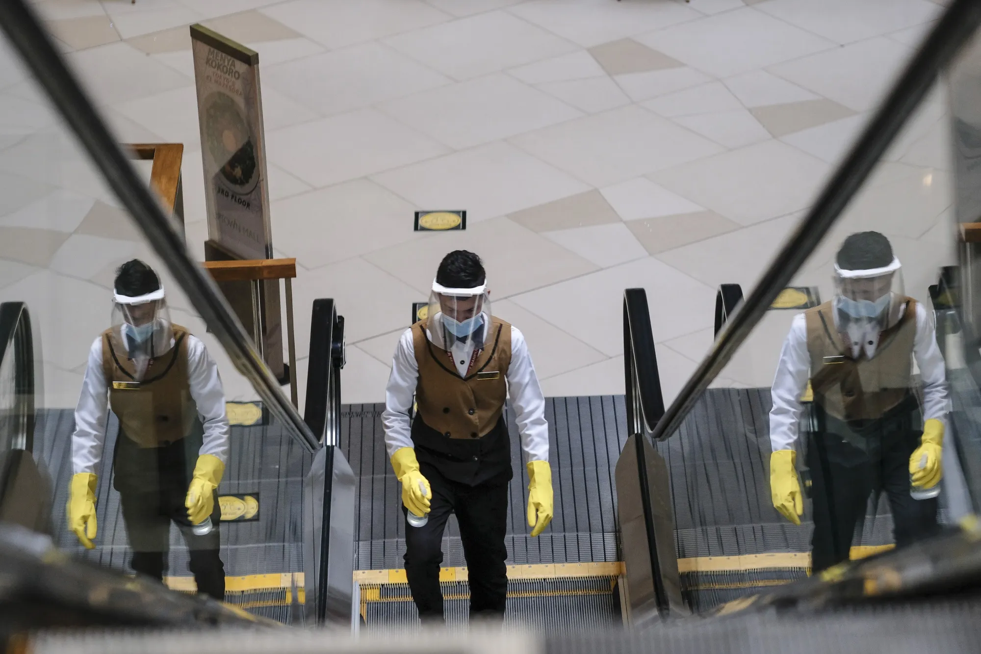 An employee sanitizes an escalator inside Megaworld Corp.'s Uptown Mall in Metro Manila on May 20.&nbsp;
