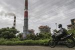 A motorcyclist travels past the Tata Power Co. Trombay Thermal Power Station in Mumbai.