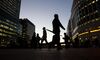 Commuters walk past the JP Morgan, left, and Thomson Reuters Corp., right, buildings illuminated at night in the Canary Wharf business, financial and shopping district of London, U.K., on Wednesday, Oct. 28, 2015. In its monthly consumer confidence index, GfK said a measure of Britons' outlook for the economy over the next 12 months dropped to minus 4 in October, the lowest reading this year.