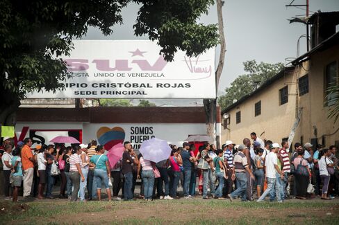 Residents wait in line to buy groceries in Charallave.