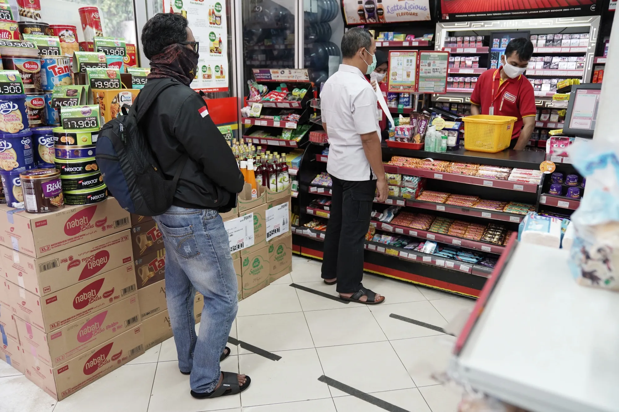 Customers&nbsp;use social distancing markers at the checkout counter of a convenience store in Jakarta on May 13.