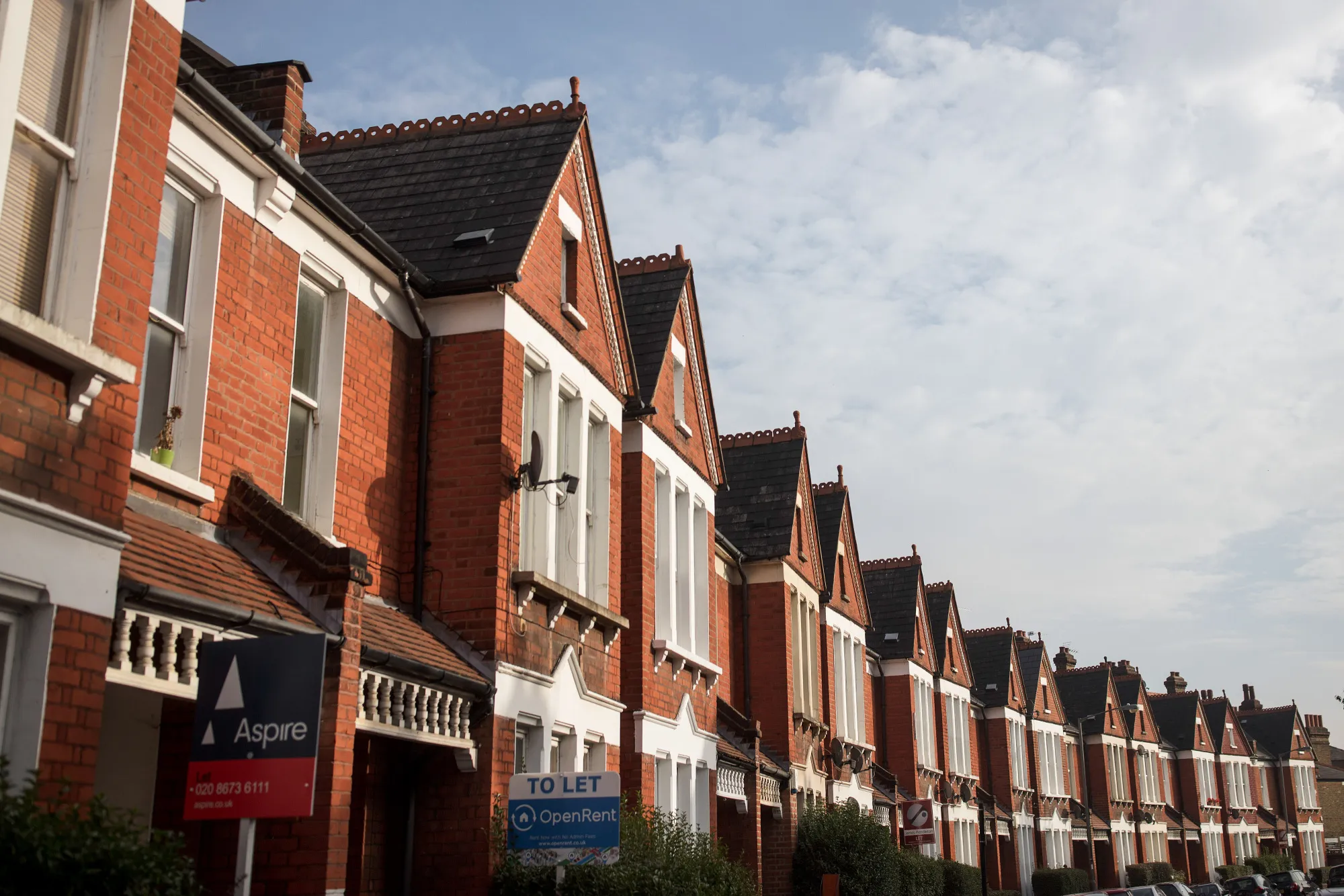 Estate agents' signs advertising properties to let&nbsp;in front of terraced houses in London.