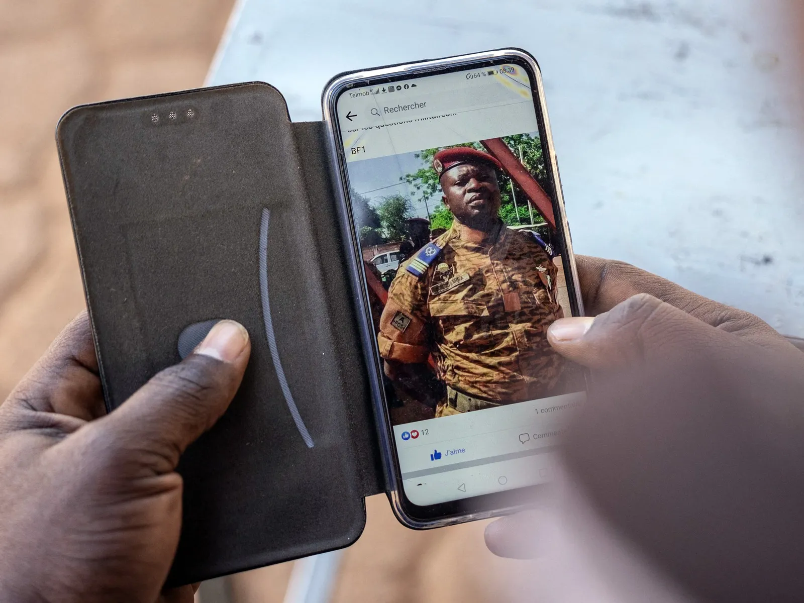 A resident&nbsp;looks on his smartphone at the picture of Paul-Henri Sandaogo Damiba.
