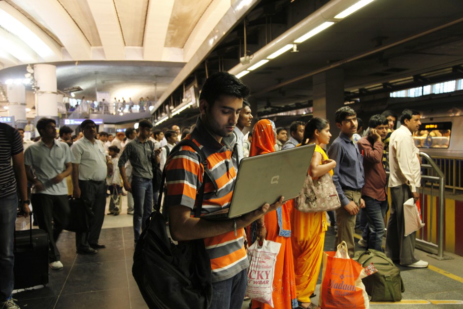 A man works on his laptop as he waits for a train at a metro station in Delhi in 2014.