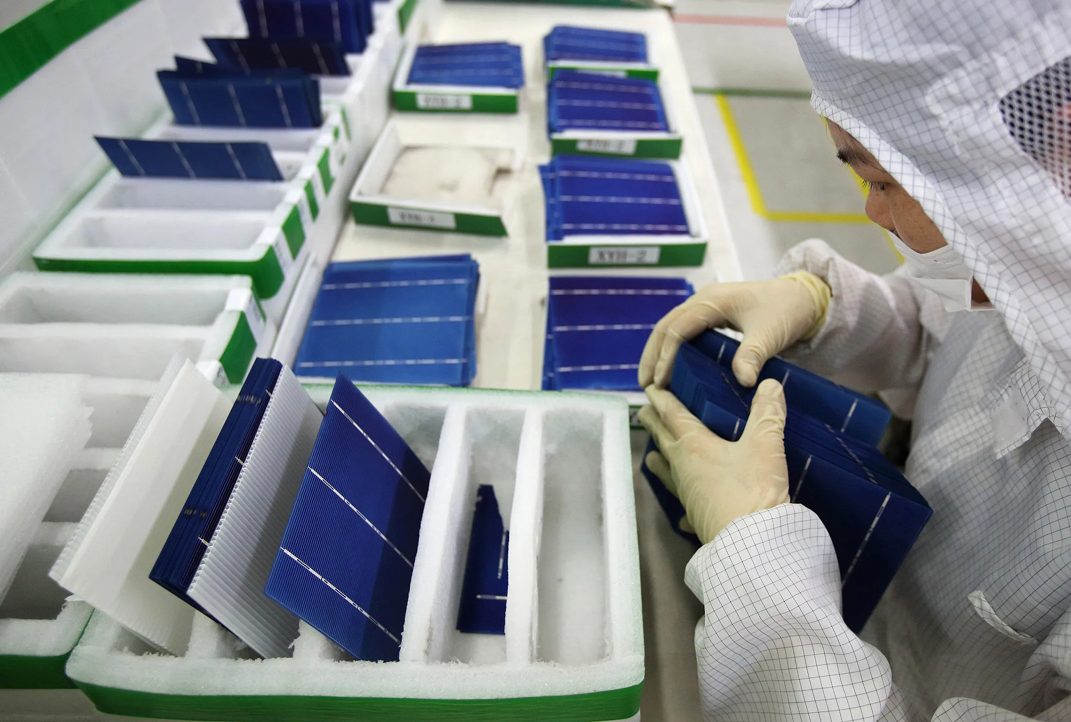 An employee performs a final inspection on solar cells on the production line