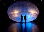 Visitors stand next to a high altitude WiFi internet hub, a Google Project Loon balloon, on display at the Airforce Museum in Christchurch.