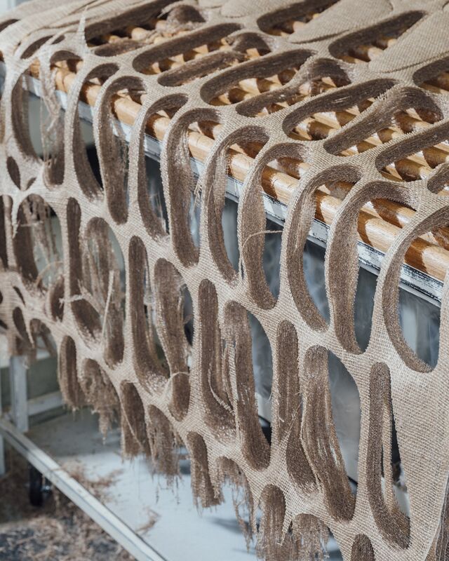 Rolls of jute being fed into a machine that will cut it into shapes.