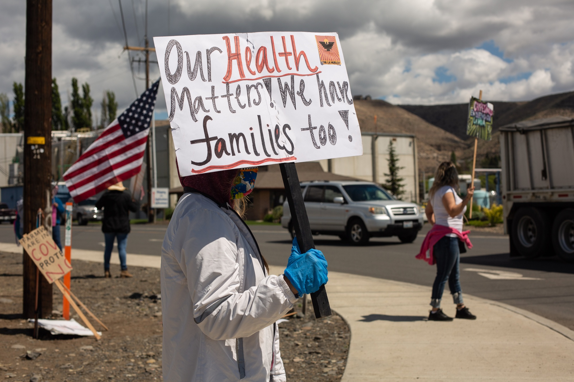 Demonstrators hold signs during a strike outside of a Allan Brothers Fruit apple packing house in Naches, Washington, on May 18, 2020.