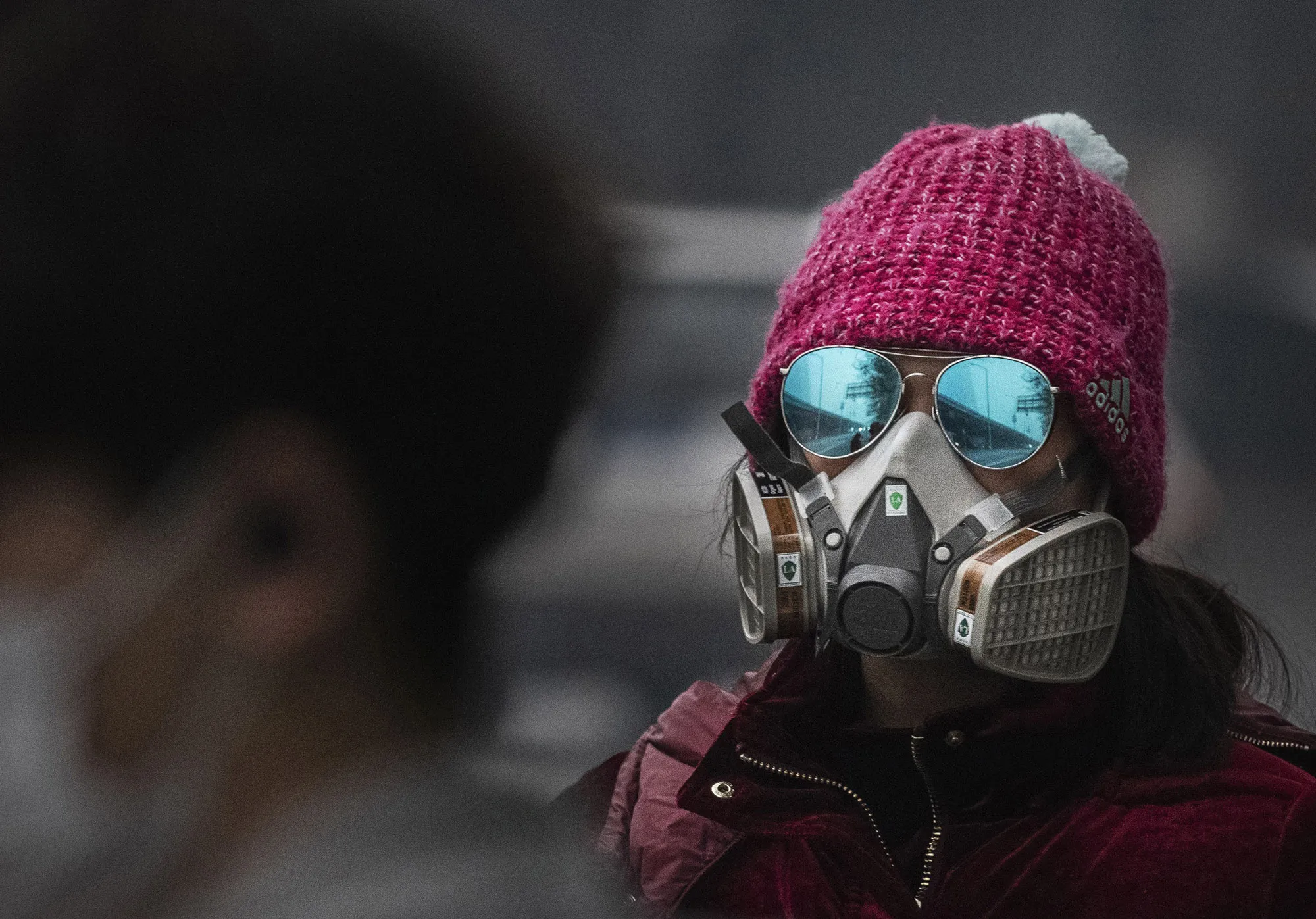 A&nbsp;woman wears a protective mask as she waits for a bus&nbsp;in Beijing&nbsp;on Feb. 13.
