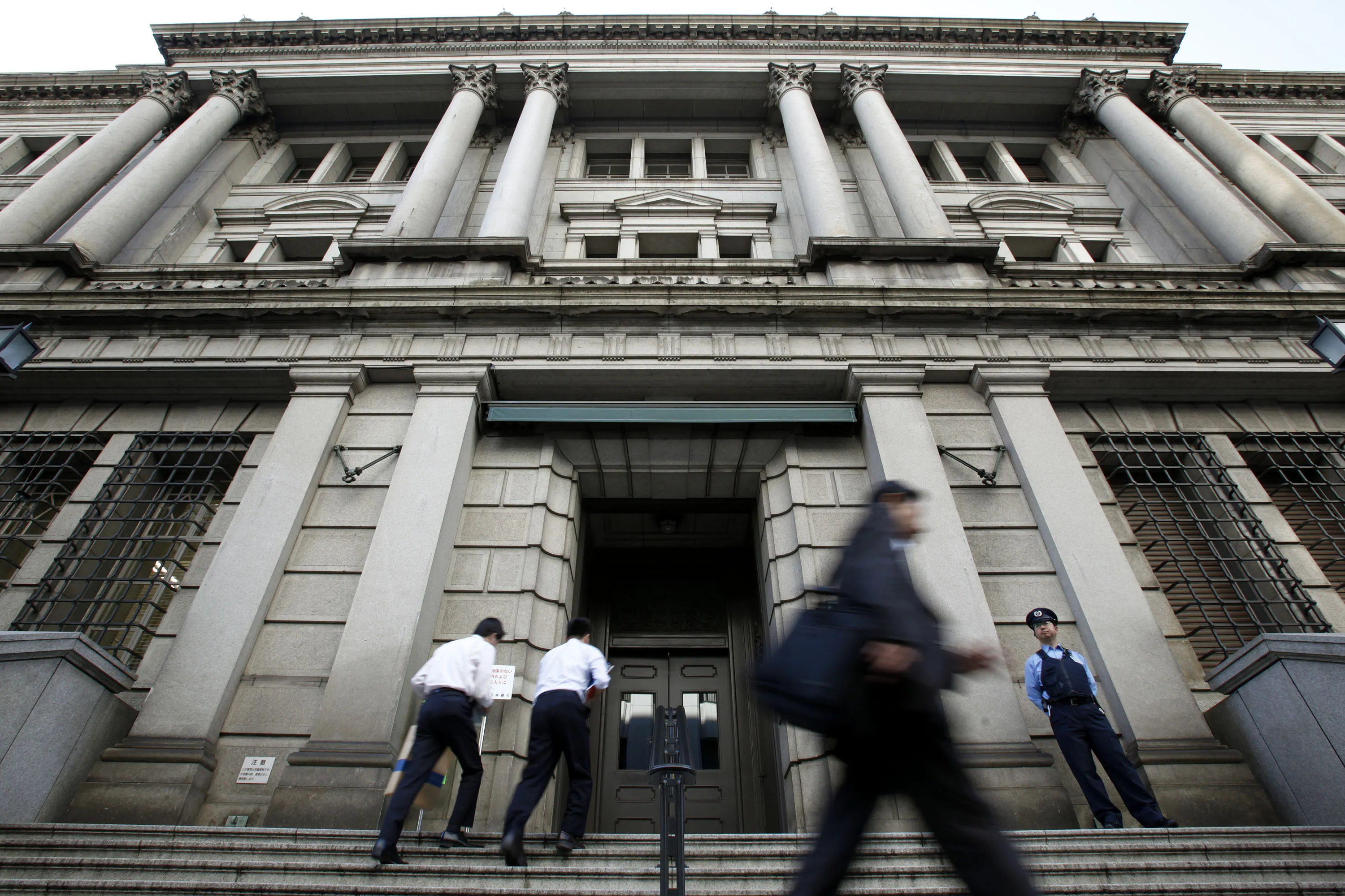Pedestrians walk past the Bank of Japan headquarters in Tokyo, Japan.