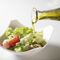 Pouring olive oil over salad leaves with tomatoes