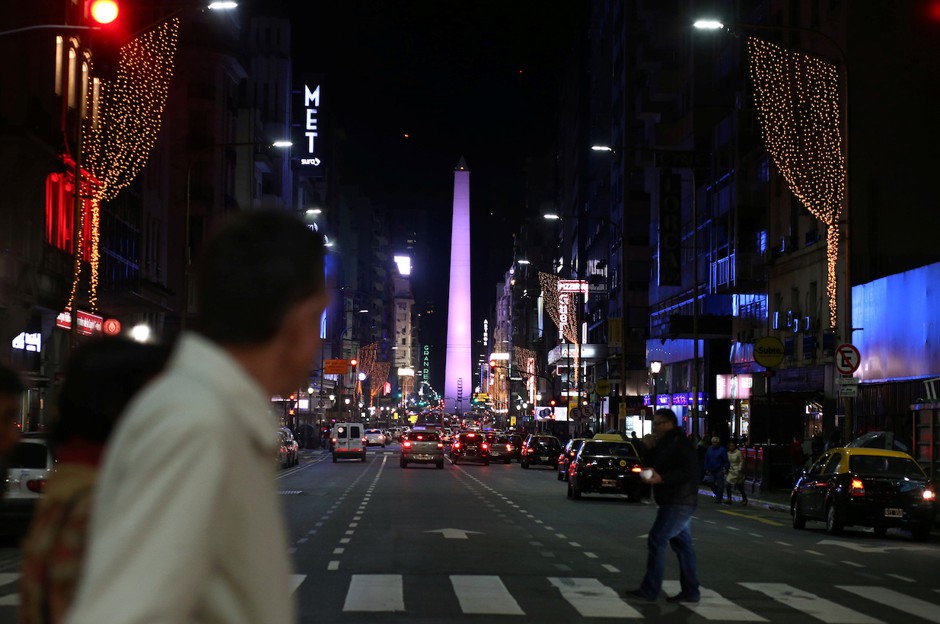 People cross Corrientes Avenue in Buenos Aires at night.