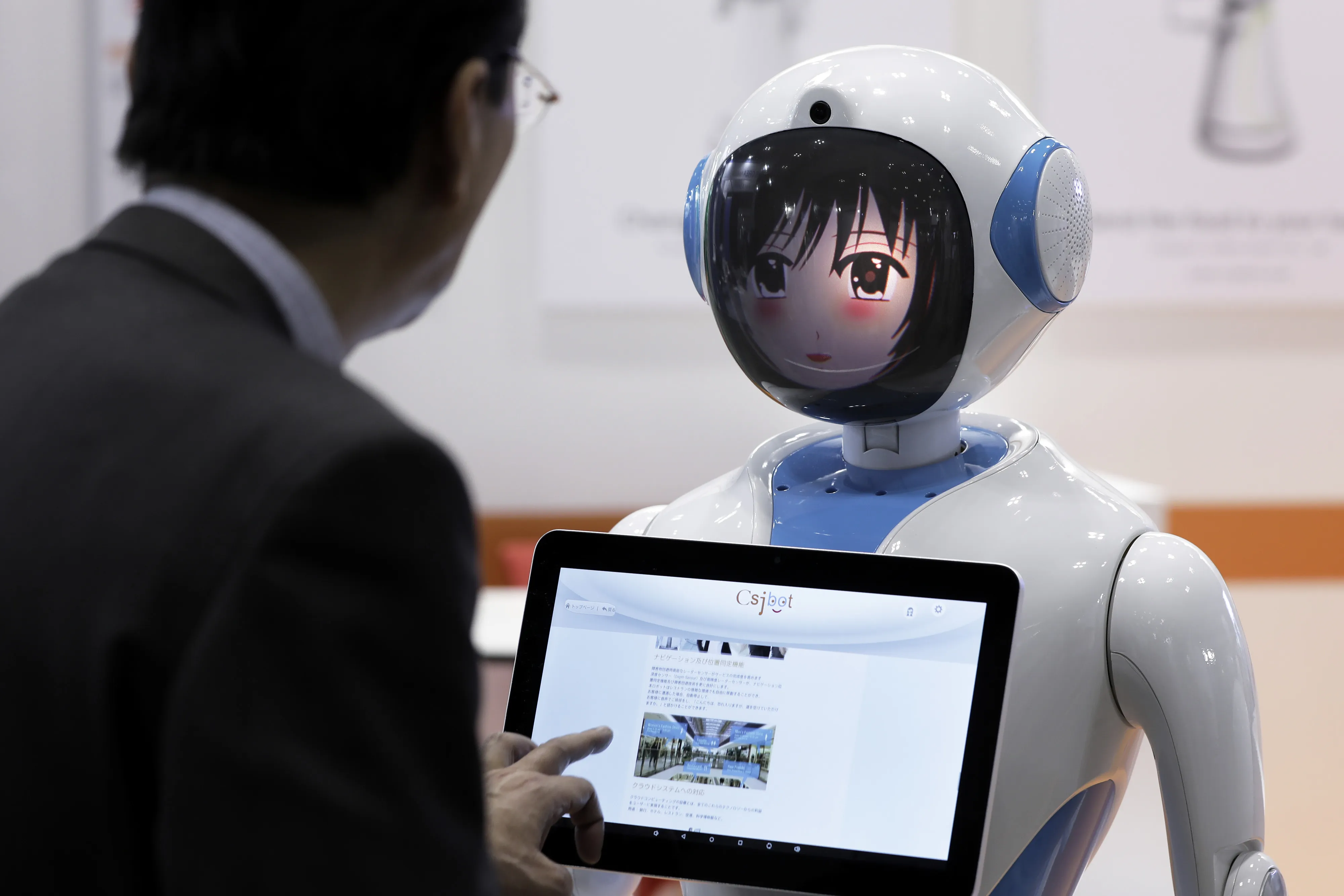 A person&nbsp;inspects a Suzhou Pangolin Robot Corp. service robot 'Alice' at the International Robot Exhibition in Tokyo.