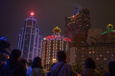 Pedestrians walk in front of the Bank of China building (left) and the Casino Grand Lisboa in Macau on March 12, 2015.