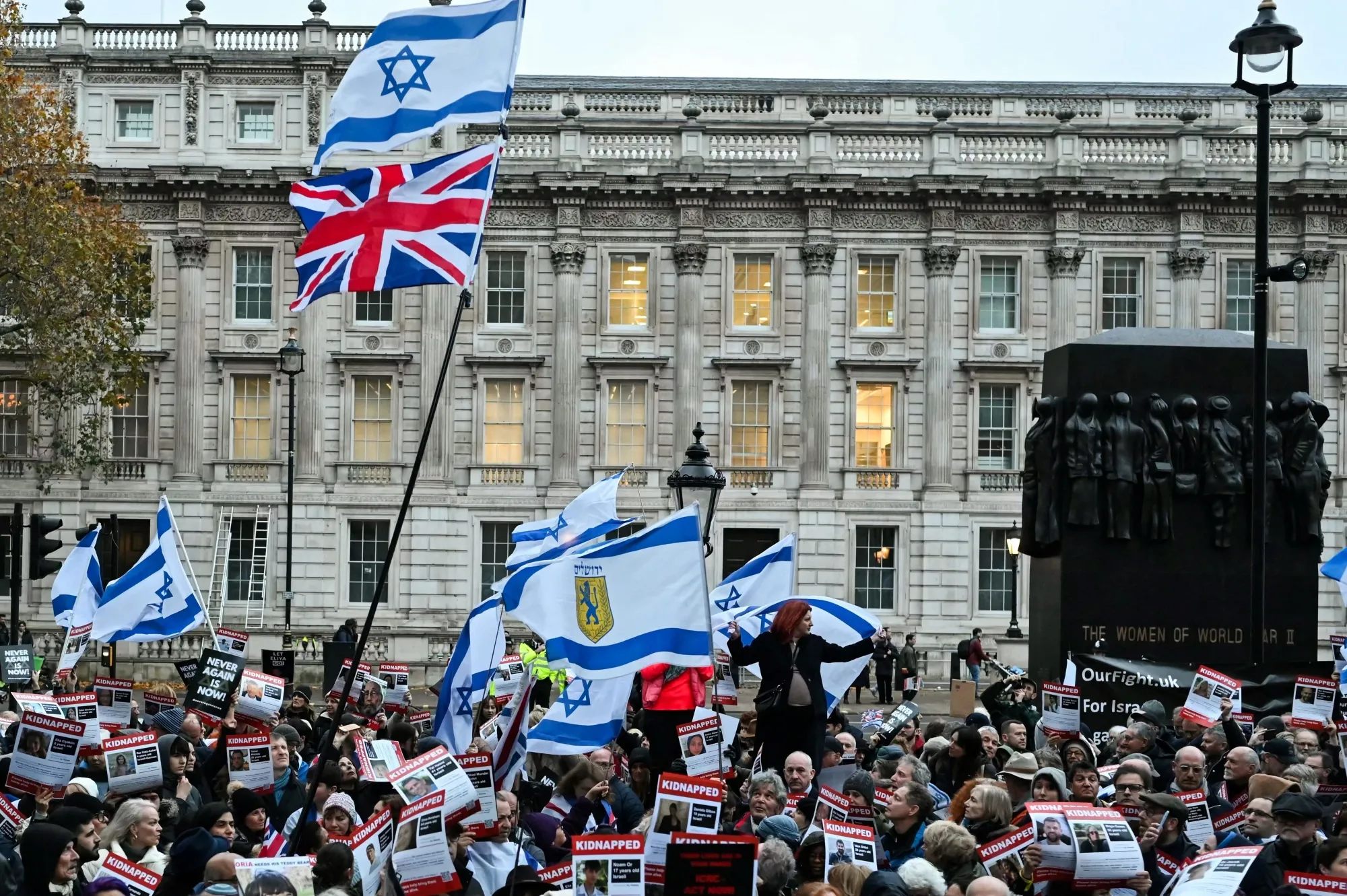 Protesters wave Israeli flags and hold photos of people held hostage by&nbsp;Hamas in Gaza, during a demonstration outside Downing Street.