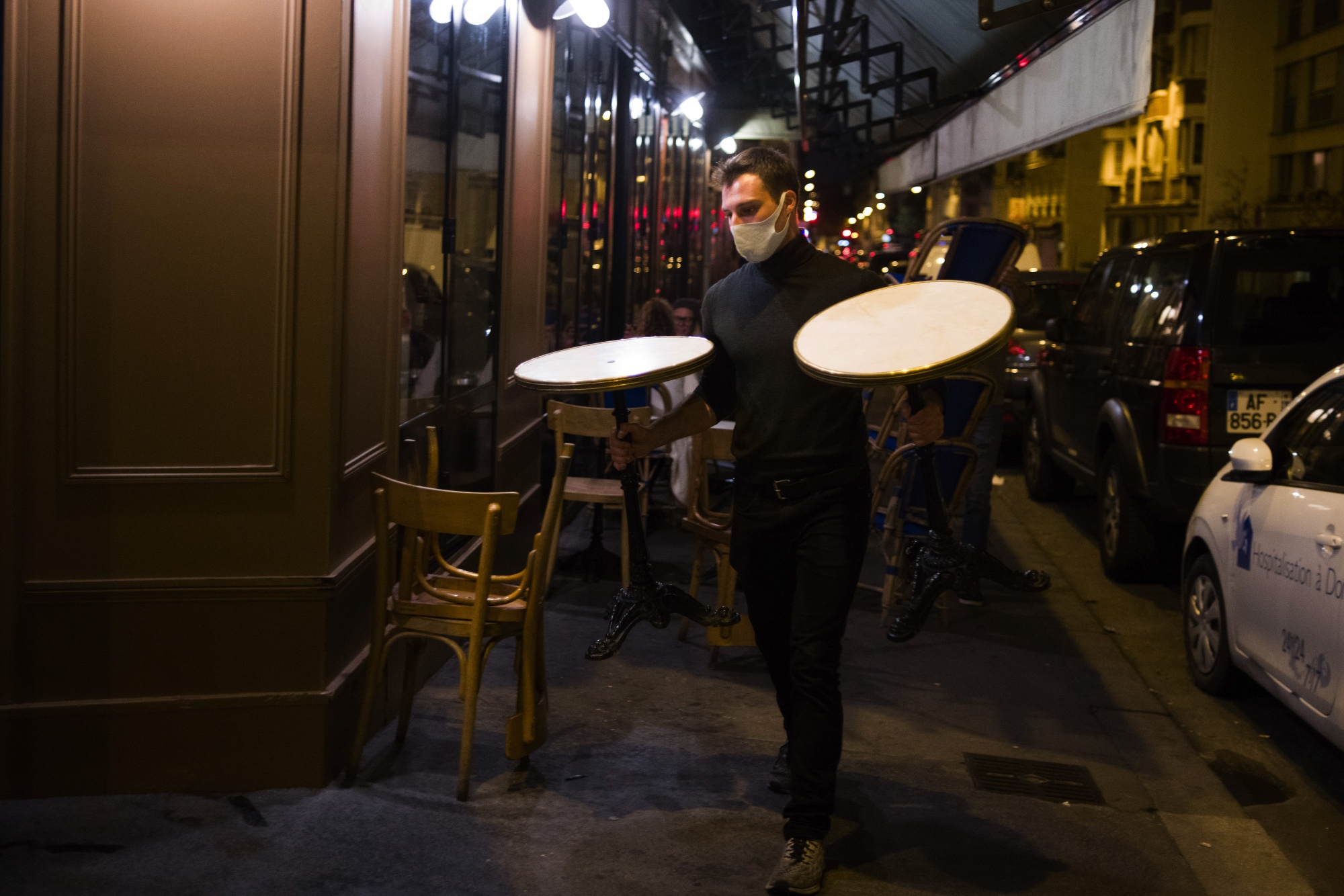 A waiter&nbsp;carries terrace tables during closing time at a restaurant&nbsp;in Paris&nbsp;on&nbsp;Sept. 28.&nbsp;