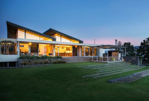 Illuminated modern house beyond yard and swimming pool at night