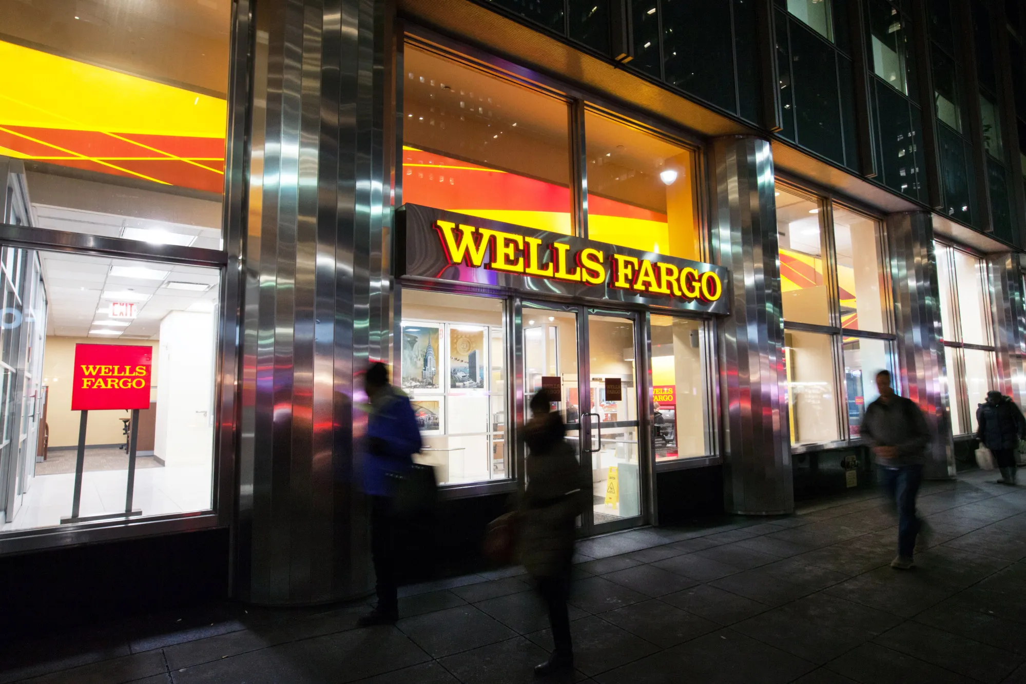 Pedestrians pass in front of a Wells Fargo & Co. bank branch in New York.