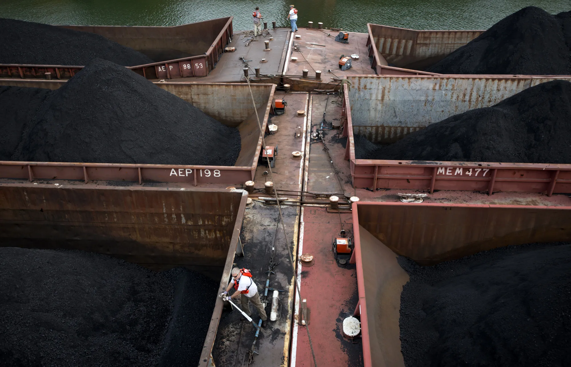 Workers tighten down lines connecting 15 barges together holding 30,000 tons of coal before making their way down the Ohio River in West Virginia, U.S.