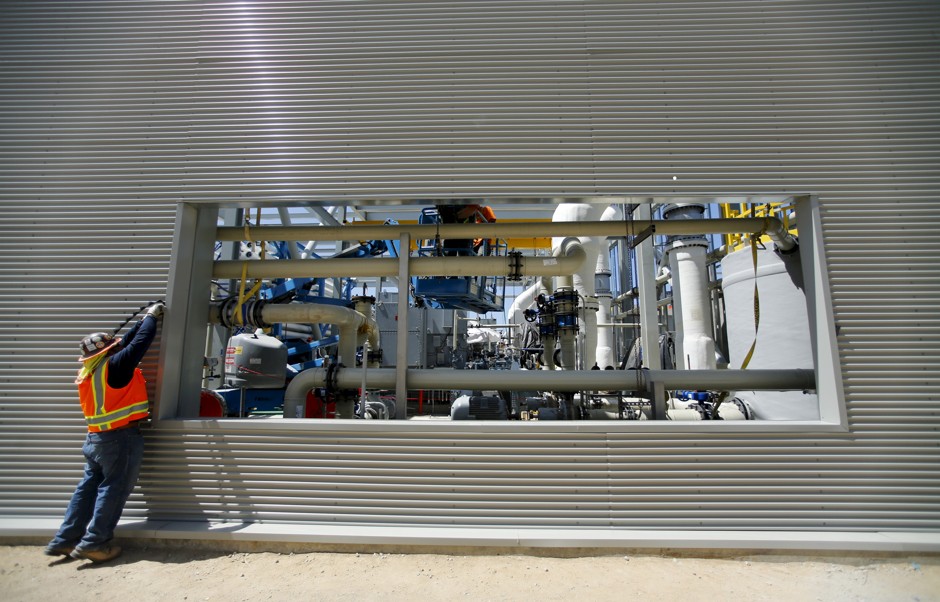 A worker fixes the siding on a wall of the seawater desalination plant in Carlsbad, California.