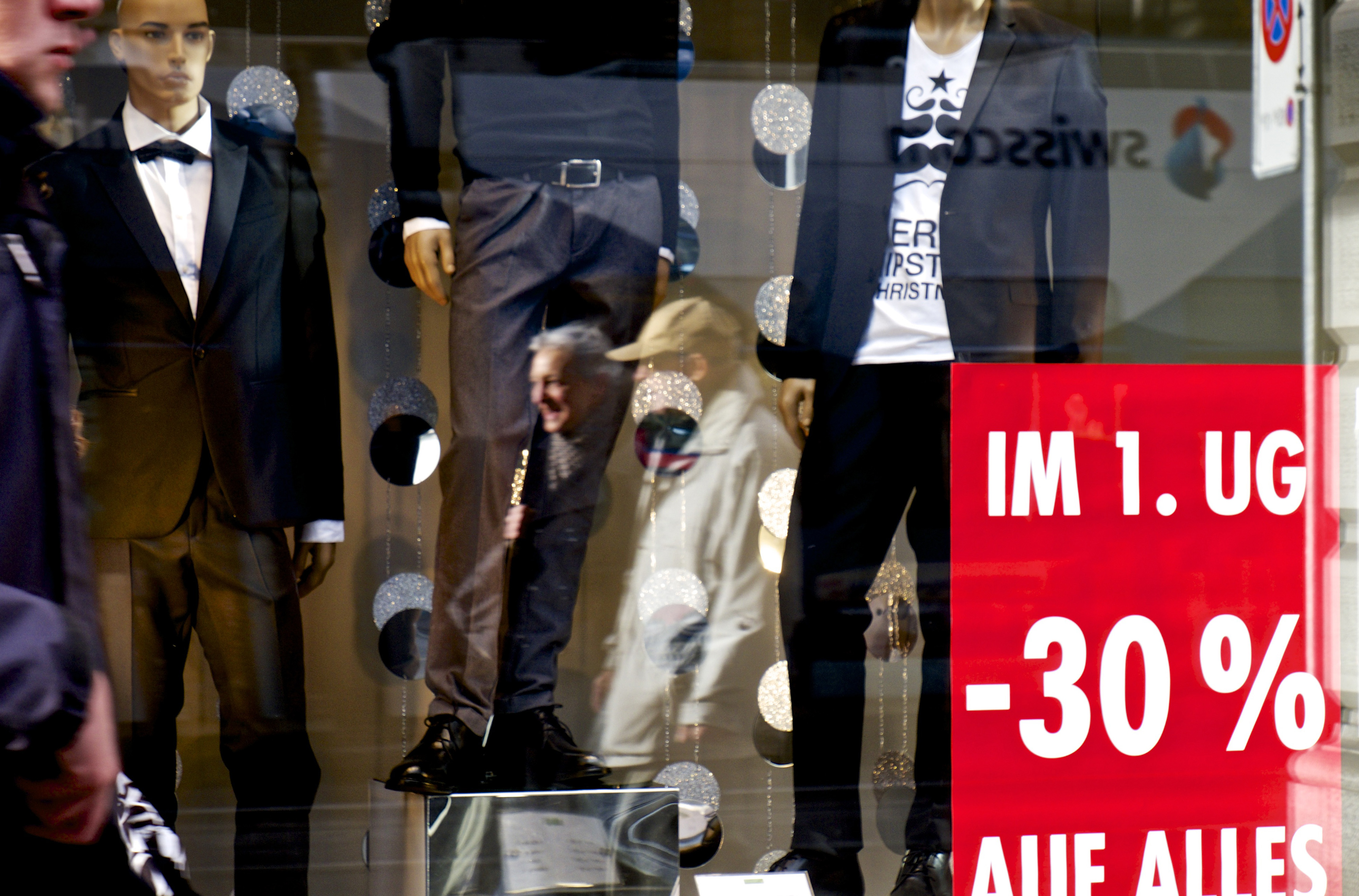 Pedestrians are reflected in the window display of a mens clothing store in Zurich, Switzerland, on Thursday, Dec. 11, 2014. 
