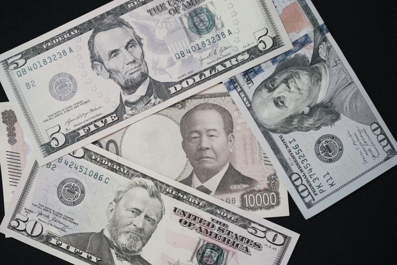 A Japanese 10,000 yen banknote with US dollar banknotes arranged for a photograph in Tokyo, Japan.