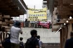 Protesters outside the Village Plaza during a media tour at the Olympic and Paralympic Village, on June 20.
