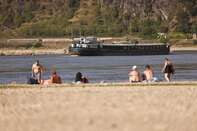 A barge passes residents on an exposed riverbed on the River Rhine near Loreley, Germany.