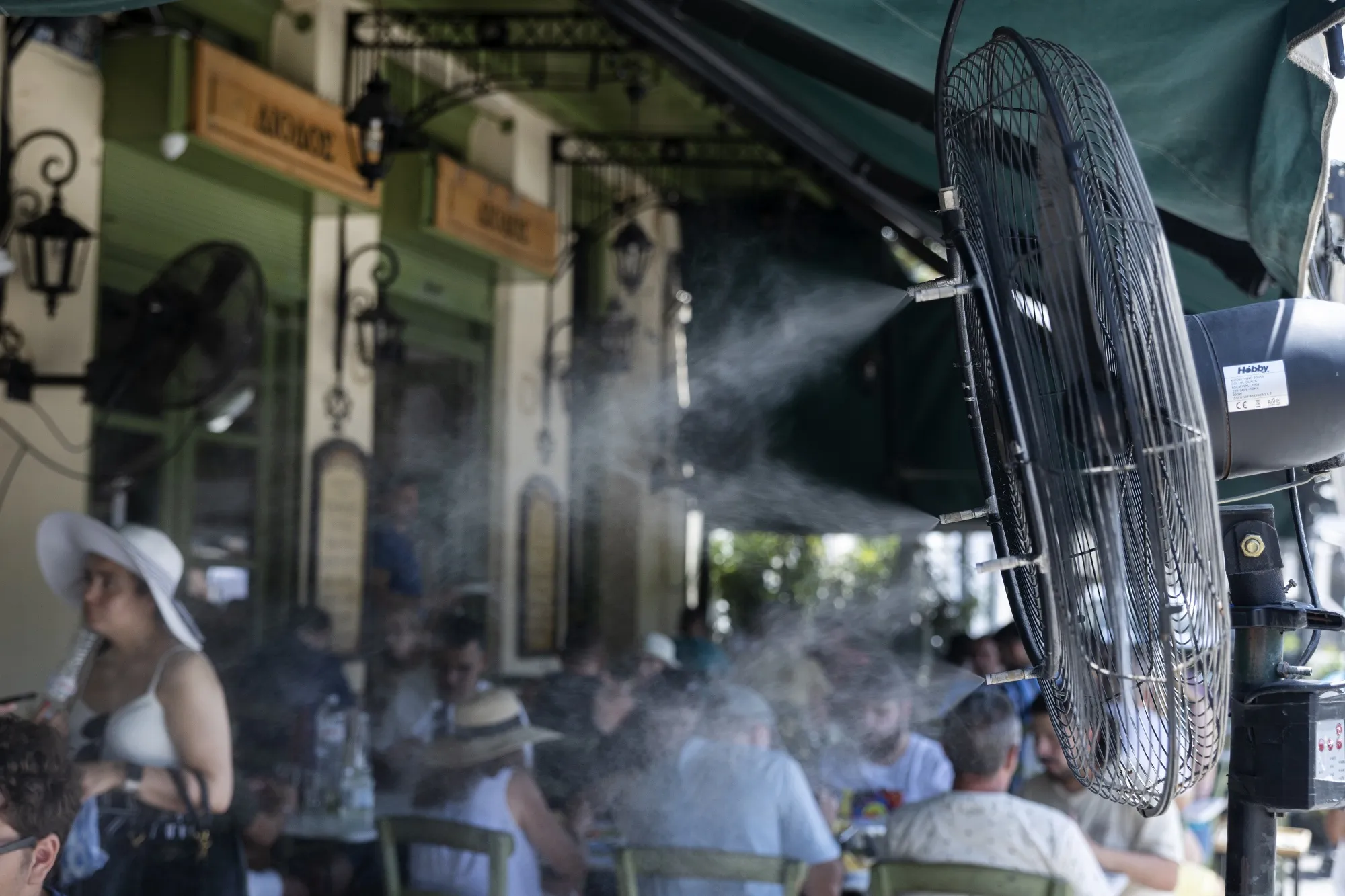 Fans and mist sprays keep restaurant customers during extreme hot weather conditions, in Athens on July 14.