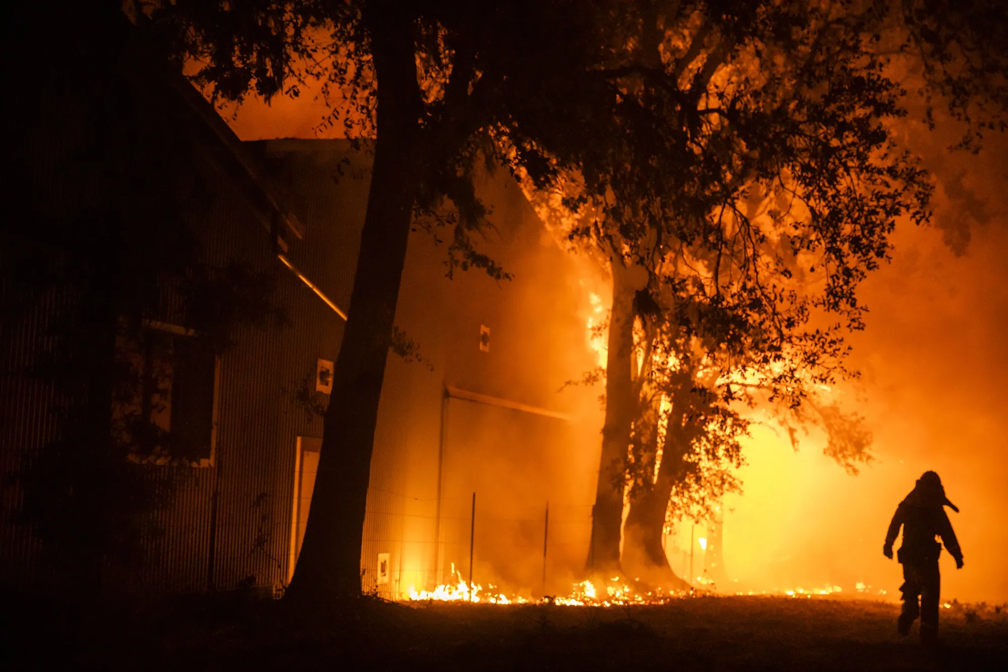 A firefighter searches the perimeter of a burning building at the Soda Rock Vineyards during the Kincade fire in Healdsburg, California.