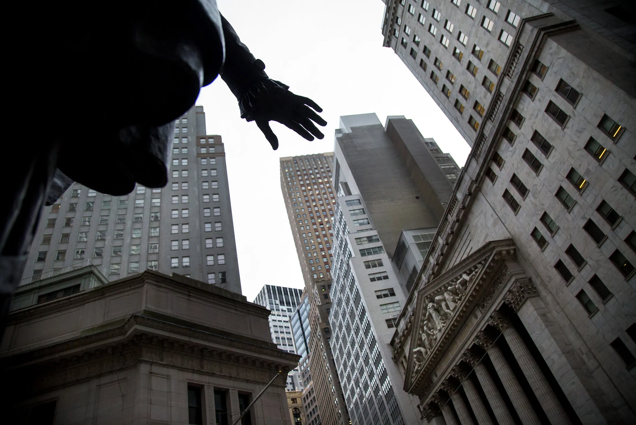 The New York Stock Exchange (NYSE) stands across Wall Street from a bronze George Washington statue in New York, U.S., on Monday, Feb. 29, 2016.
