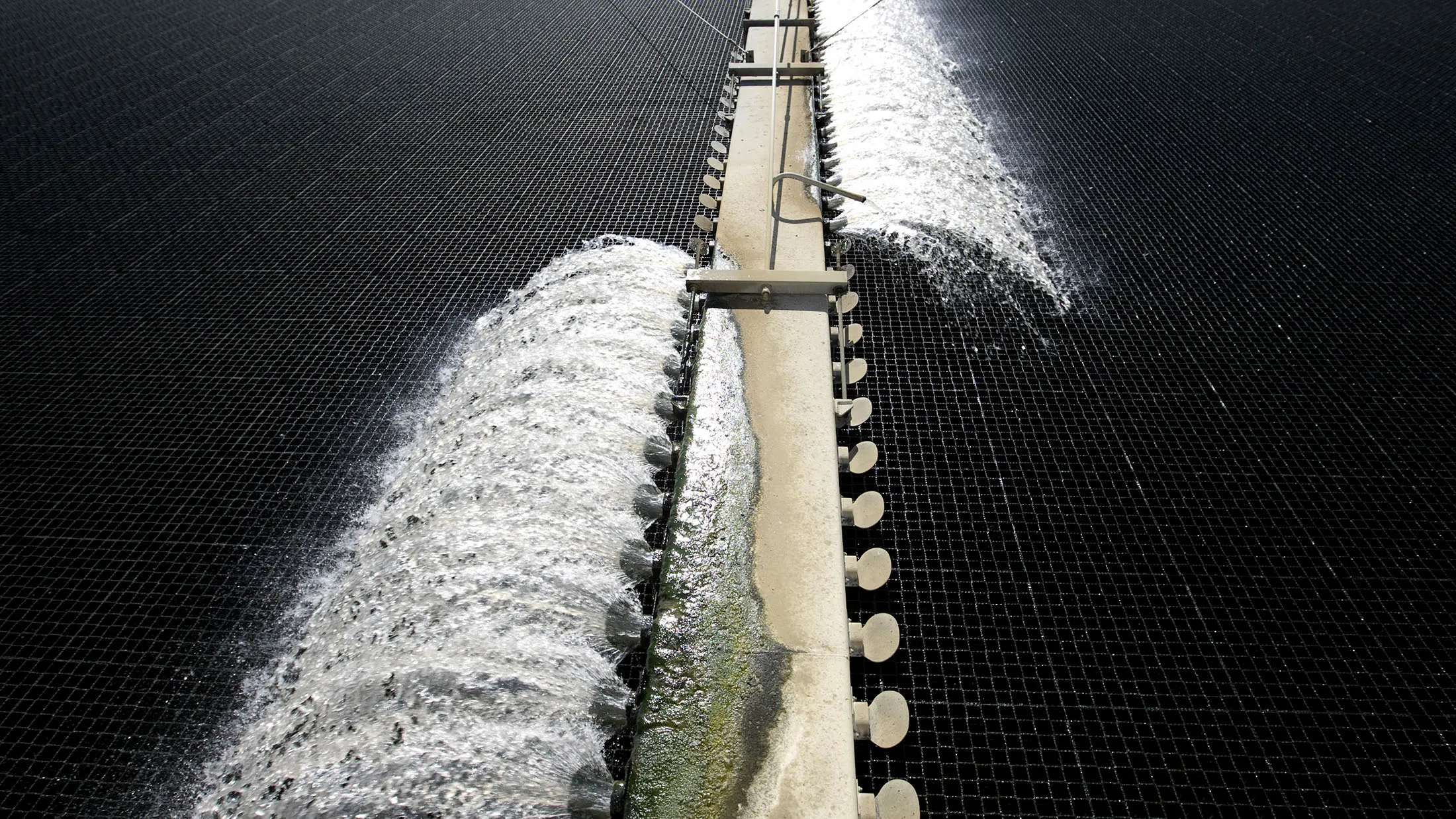 Water pours out of a trickling filter structure where the fi