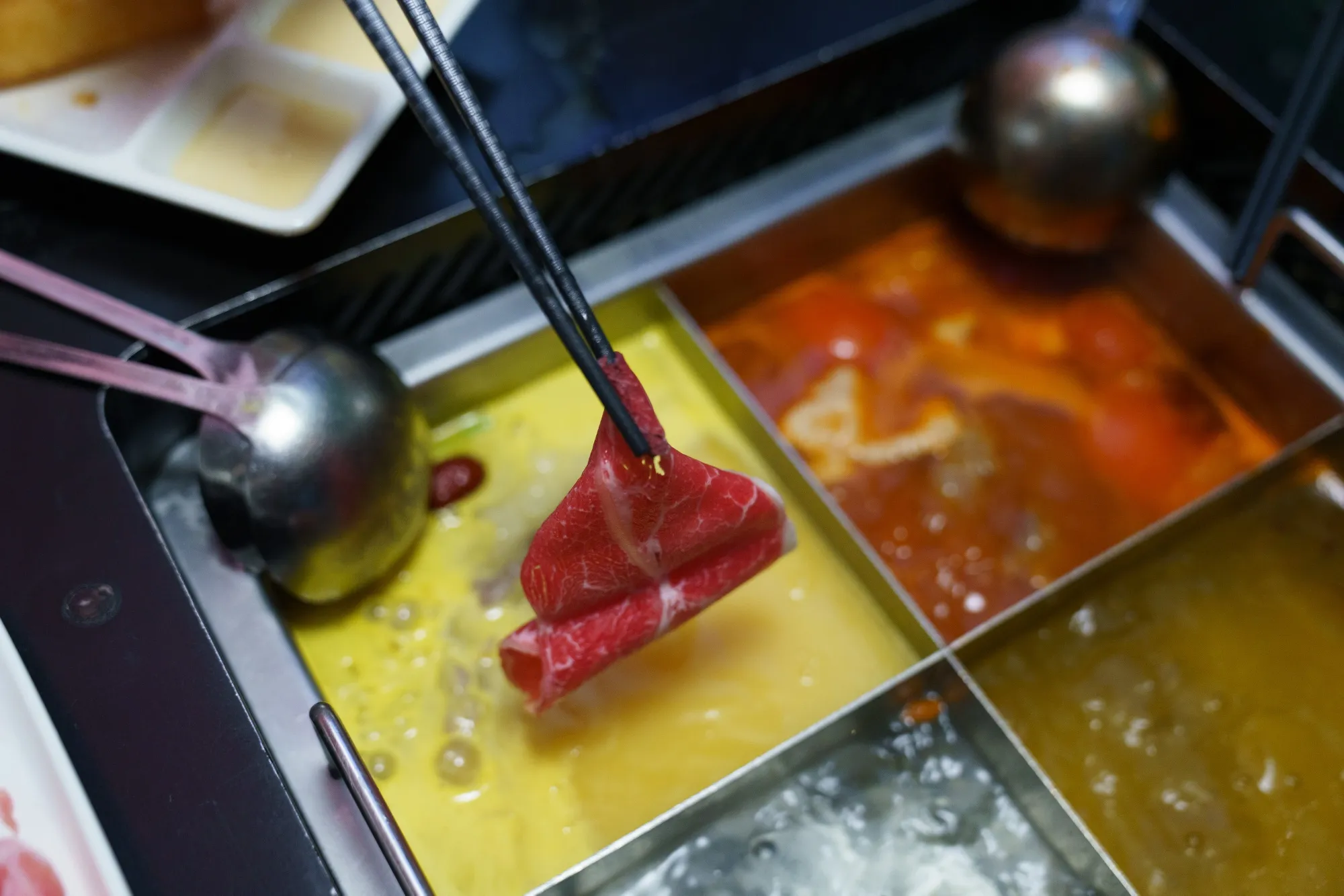 Customers cook raw food in a pot at a Haidilao hotpot restaurant in Singapore.