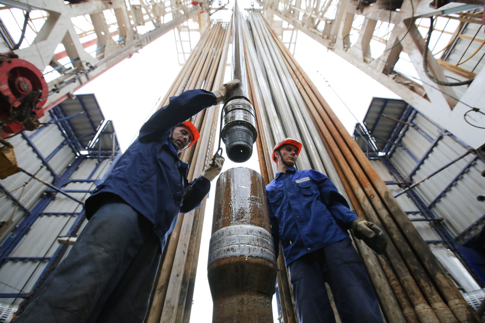 Workers secure drilling pipe sections on an oil drilling tower near Almetyevsk, Russia.